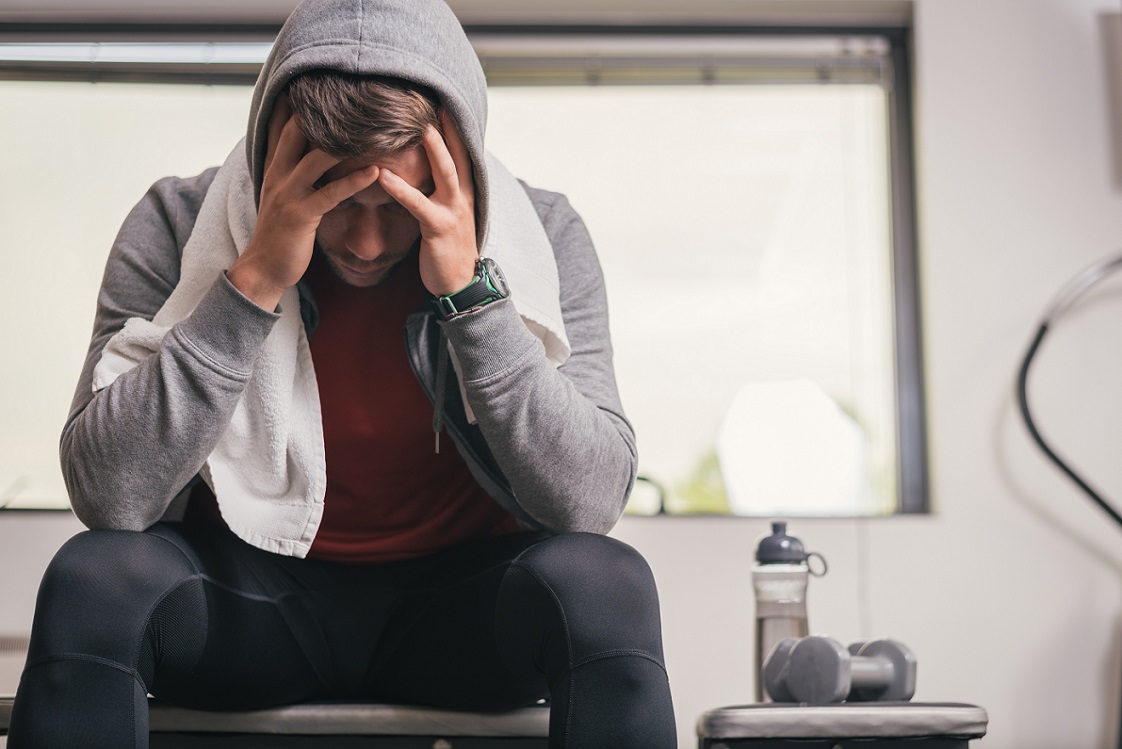 Athlete sitting on gym bench suffering mentally