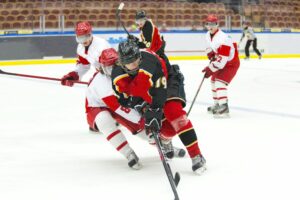 Two hockey players chase the puck during a game.