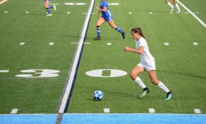 Une joueuse de football donne un coup de pied au ballon sur le terrain. 