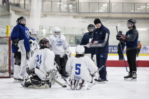 Des jeunes gardiens de but de hockey qui reçoivent l'enseignement d'un entraîneur