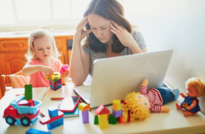 une maman qui a l'air stressée alors qu'elle est assise à table pour aider son enfant