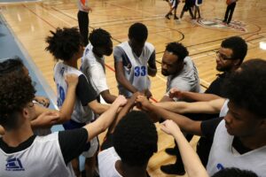 Un entraîneur et des joueurs de basketball BIPOC en réunion sur la ligne de touche d'un terrain de basketball